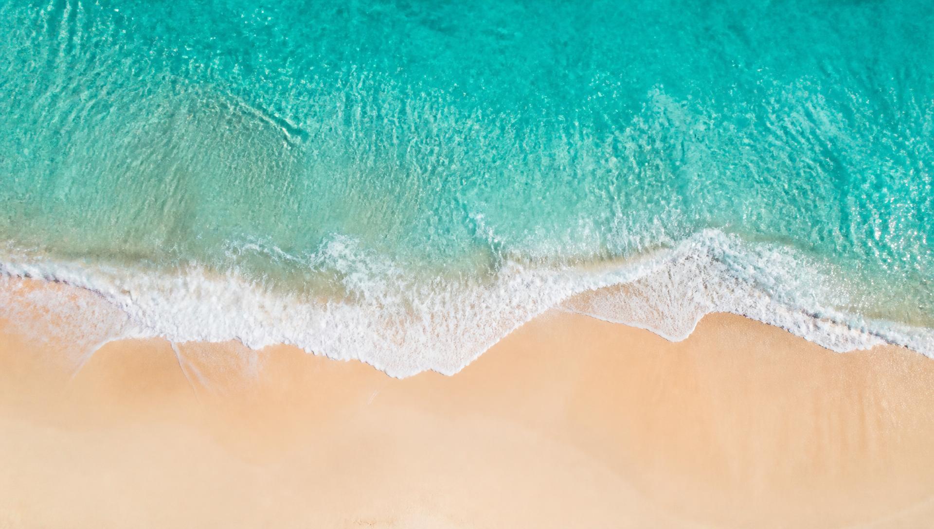 Calm turquoise shoreline meeting soft sand